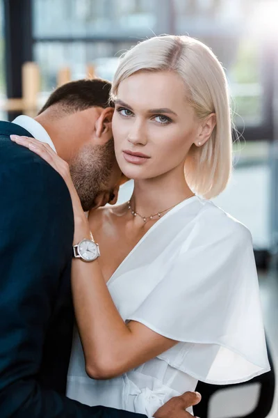 Bearded man hugging attractive blonde woman looking at camera — Stock Photo