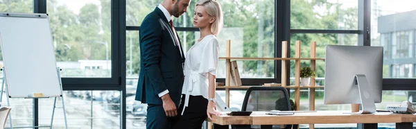 Plan panoramique de bel homme d'affaires touchant attrayant jeune femme tout en flirtant dans le bureau — Photo de stock