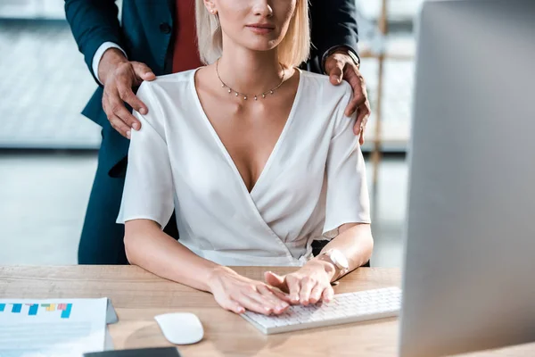 Ausgeschnittener Blick auf Geschäftsmann, der steht und die Schultern der blonden Frau berührt — Stockfoto