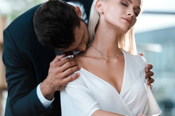 Bearded man kissing neck of attractive blonde woman in office — Stock Photo