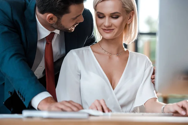 Selective focus of handsome man looking at happy blonde colleague — Stock Photo