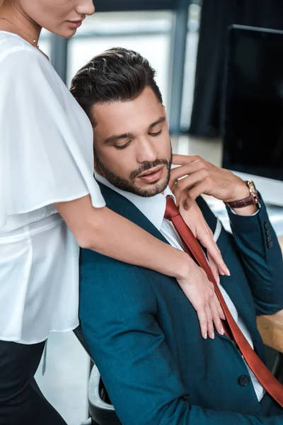 Vista ritagliata della donna in piedi vicino bello uomo barbuto in ufficio — Foto stock