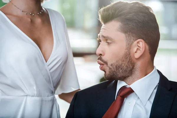 Selective focus of surprised man looking at breasts of woman in office — Stock Photo