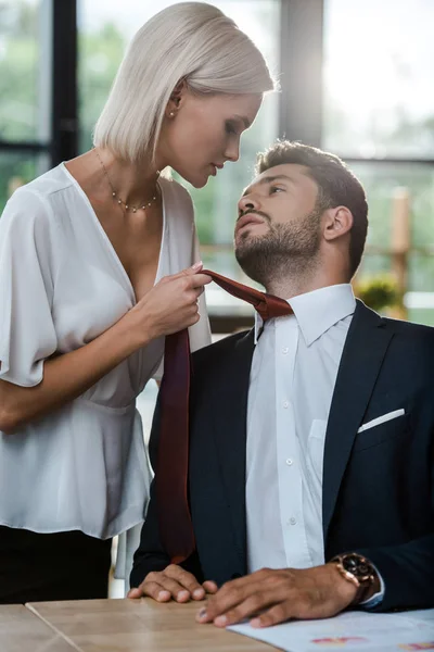 Femme passionnée touchant cravate de bel homme tout en flirtant dans le bureau — Photo de stock