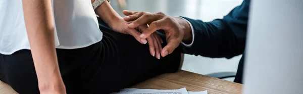 Panoramic shot of man and woman holding hands in office — Stock Photo