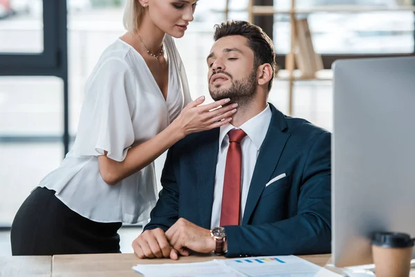 Selektiver Fokus der Frau berührt Gesicht eines bärtigen Geschäftsmannes beim Flirten im Büro — Stockfoto