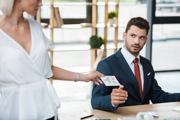 Recortado vista de mujer rubia sosteniendo tarjeta con me llaman letras cerca sorprendido hombre de negocios - foto de stock