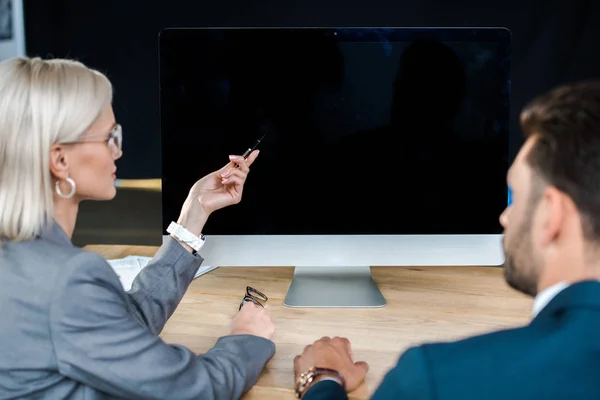 Enfoque selectivo de monitor de computadora con pantalla en blanco cerca de hombre de negocios y mujer de negocios - foto de stock