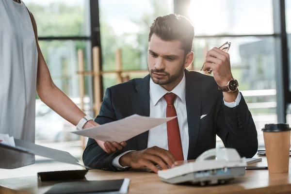 Cropped view of woman holding document near businessman in office — Stock Photo