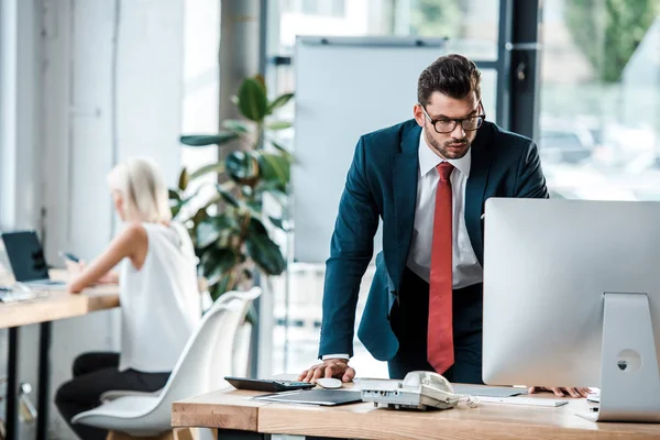 Selektiver Fokus eines gutaussehenden Mannes, der im Büro auf den Computermonitor blickt — Stockfoto