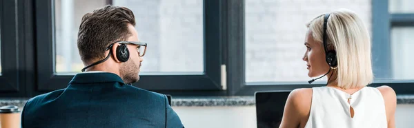 Panoramic shot of operators in headsets looking at each other in office — Stock Photo