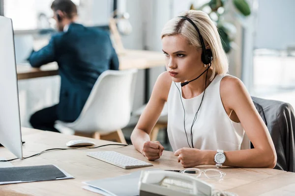 Selective focus of emotional woman in headset gesturing in office — Stock Photo