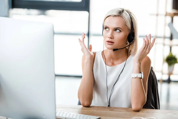 Selective focus of beautiful operator in headset gesturing in office — Stock Photo