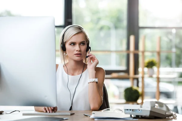 Selective focus of beautiful operator touching headset while working in office — Stock Photo