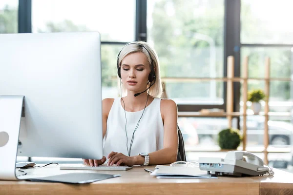 Selective focus of attractive blonde operator working in office — Stock Photo