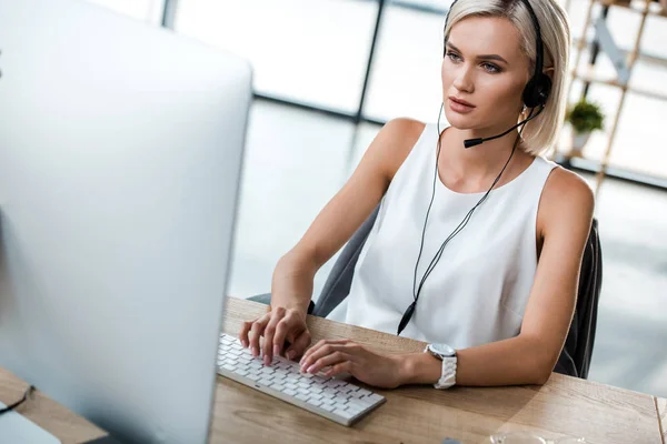 Enfoque selectivo de la mujer atractiva en la escritura de auriculares en el teclado de la computadora - foto de stock