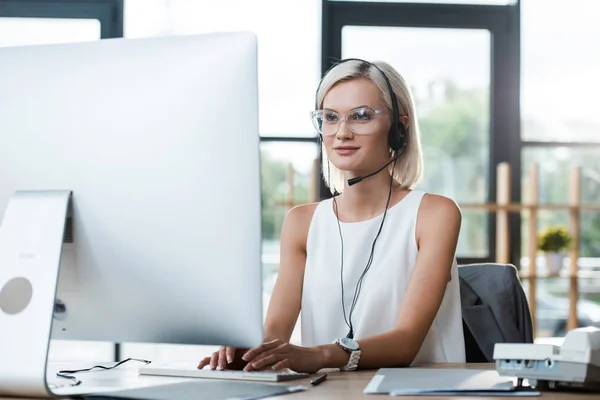 Selective focus of happy blonde operator in glasses working in call center — Stock Photo