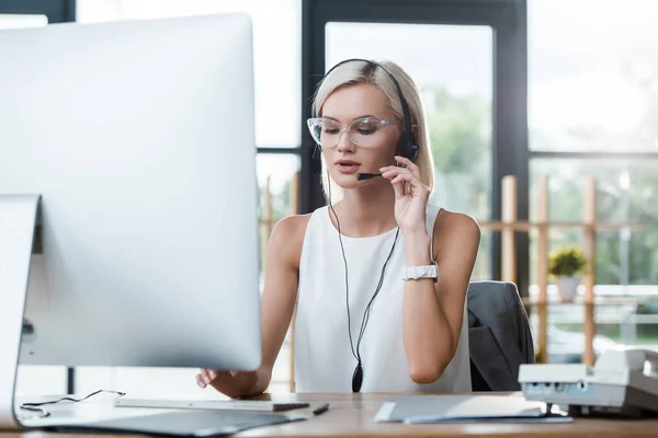 Selective focus of attractive blonde operator in glasses working in call center — Stock Photo