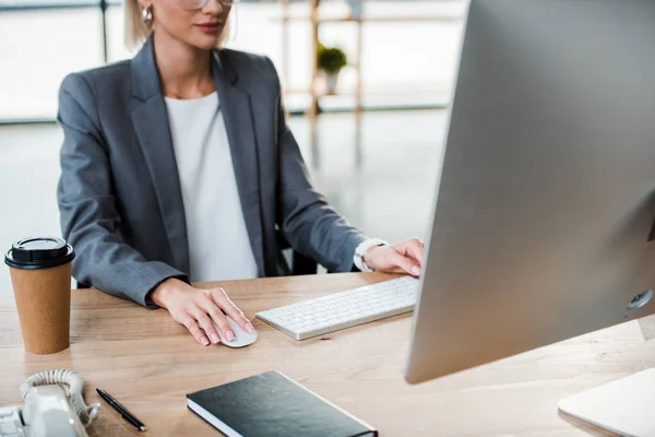 Abgeschnittene Ansicht einer Geschäftsfrau, die in einem modernen Büro in der Nähe von Pappbechern arbeitet — Stockfoto