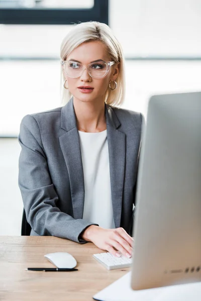 Вибірковий фокус красивої бізнес-леді в окулярах, що працюють в сучасному офісі — стокове фото