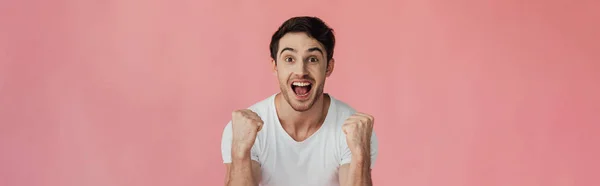 Panoramic shot of excited young man smiling at camera and showing yes gesture isolated on pink — Stock Photo