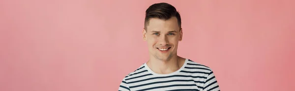 Panoramaaufnahme eines lächelnden jungen Mannes, der isoliert auf rosa Kamera blickt — Stockfoto