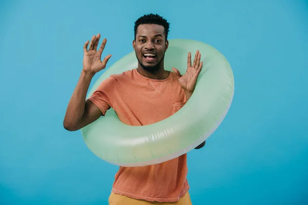 Emotional african american man standing with inflatable ring isolated on blue — Stock Photo