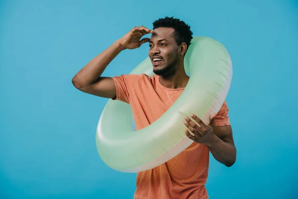 Heureux homme afro-américain debout avec anneau de natation et geste isolé sur bleu — Photo de stock