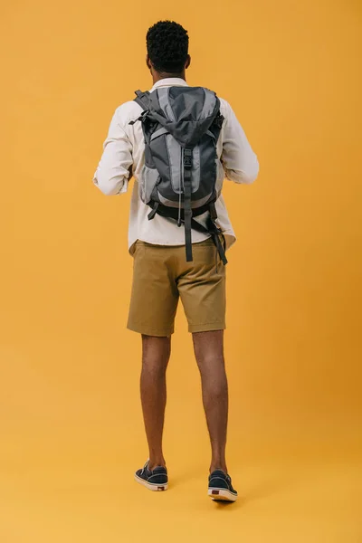 Back view of african american man standing with backpack on orange — Stock Photo