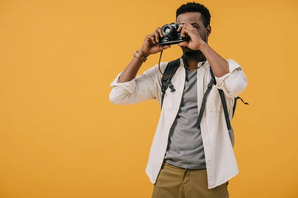 Afrikanischer amerikanischer Fotograf bedeckt Gesicht mit Digitalkamera isoliert auf orange — Stockfoto