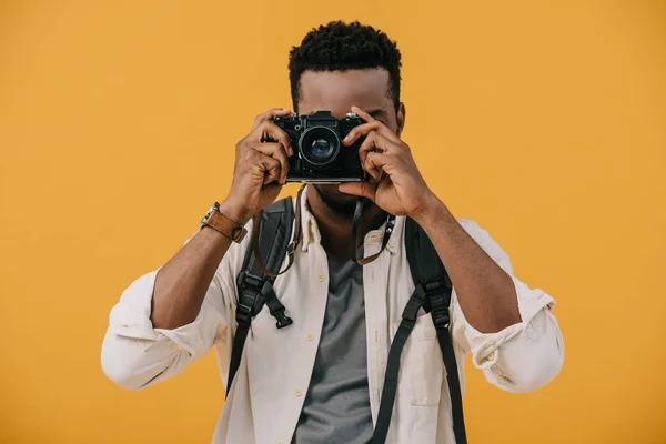 Curly african american photographer covering face with digital camera isolated on orange — Stock Photo