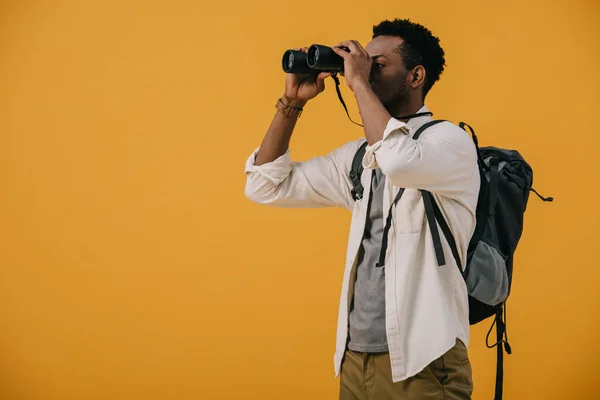 Afrikanisch-amerikanischer Mann blickt durch ein Fernglas isoliert auf orange — Stockfoto