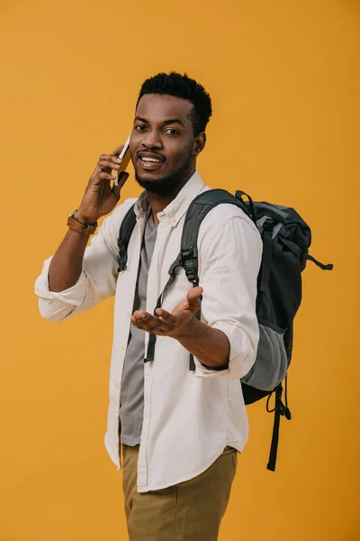 Happy african american man talking on smartphone while standing isolated on orange — Stock Photo