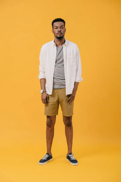 Handsome and curly african american man looking at camera on orange — Stock Photo