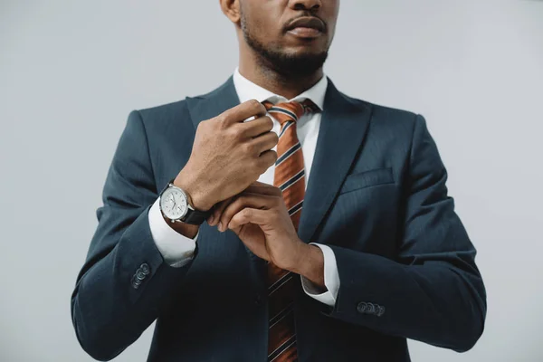 Vista recortada del hombre afroamericano tocando reloj aislado en gris - foto de stock