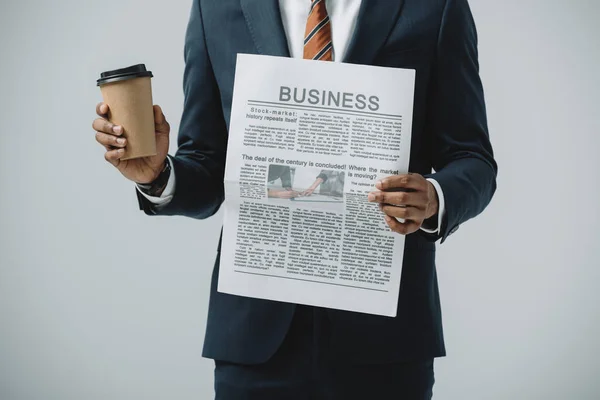 Vista recortada del hombre afroamericano sosteniendo taza desechable y periódico de negocios aislado en gris - foto de stock