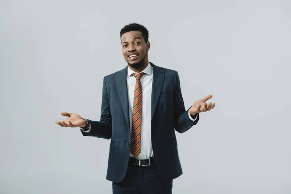 Hombre afroamericano feliz mostrando gesto de encogimiento aislado en gris - foto de stock