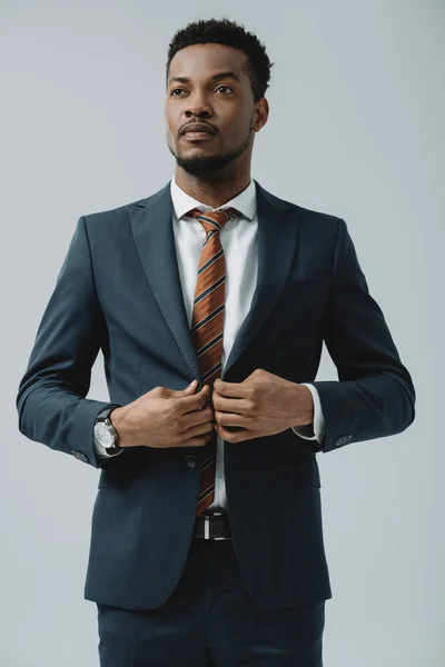 Handsome african american man touching formal wear isolated on grey — Stock Photo