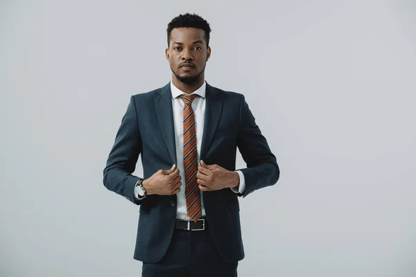 Erfolgreicher Geschäftsmann berührt Anzug isoliert auf grau — Stockfoto