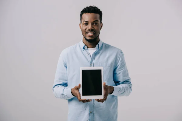 Heureux homme afro-américain tenant tablette numérique avec écran blanc isolé sur gris — Photo de stock