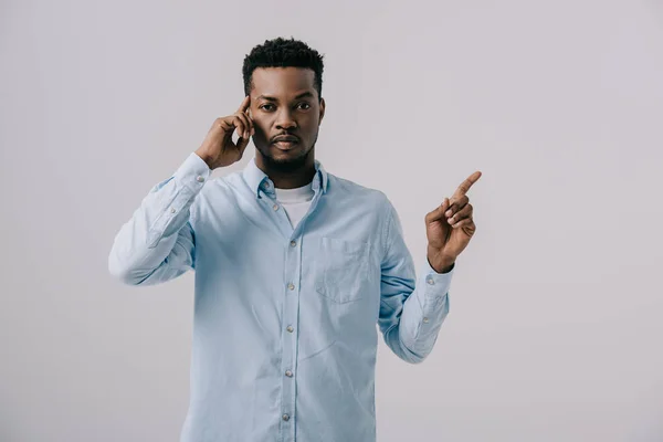 Handsome african american man touching temple and pointing with finger isolated on grey — Stock Photo