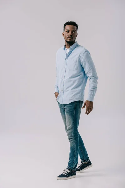 Ernster afrikanisch-amerikanischer Mann steht mit der Hand in der Tasche auf grau — Stockfoto