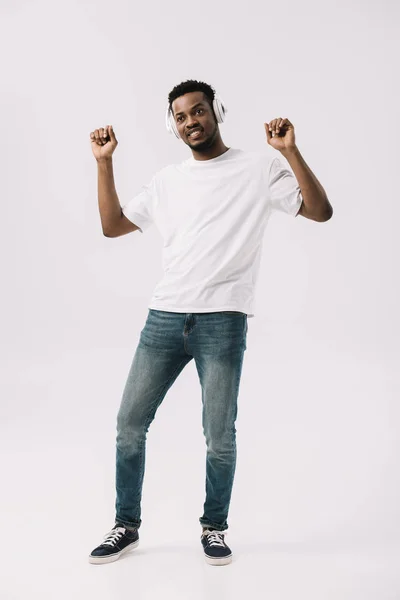 Щасливий афроамериканський чоловік слухає музику в навушниках і танцює ізольовано на білому — стокове фото