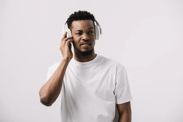 African american man listening music while touching headphones isolated on white — Stock Photo