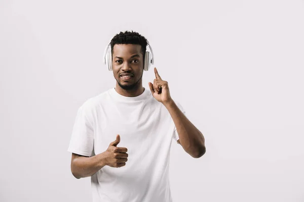 Красивий афроамериканський чоловік слухає музику і показує великий палець вгору ізольовано на білому — стокове фото