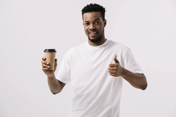 Homme afro-américain joyeux tenant tasse en papier et montrant pouce vers le haut isolé sur blanc — Photo de stock