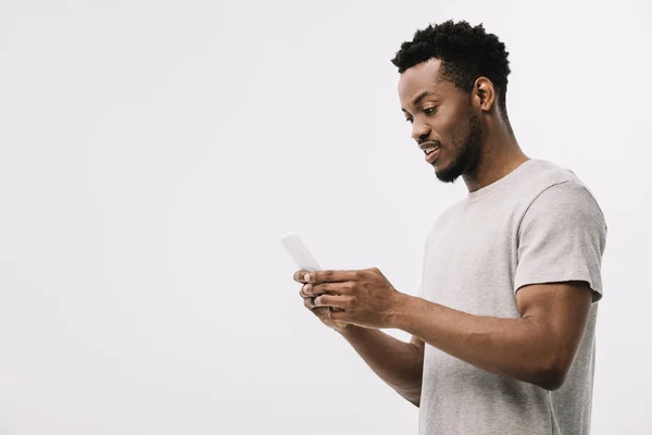 Hombre afroamericano guapo mirando teléfono inteligente aislado en blanco — Stock Photo