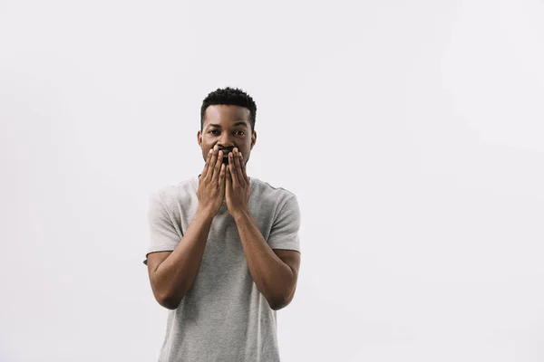 Frisé afro-américain homme couvrant la bouche et regardant caméra isolé sur blanc — Photo de stock