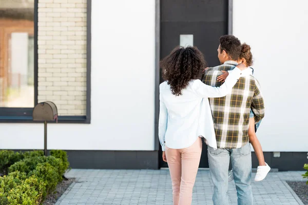 Back view of father holding kid and mother hugging husband — Stock Photo