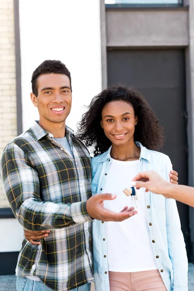 Africano americano pareja mirando cámara y sonriendo mientras tomando llave de nueva casa - foto de stock